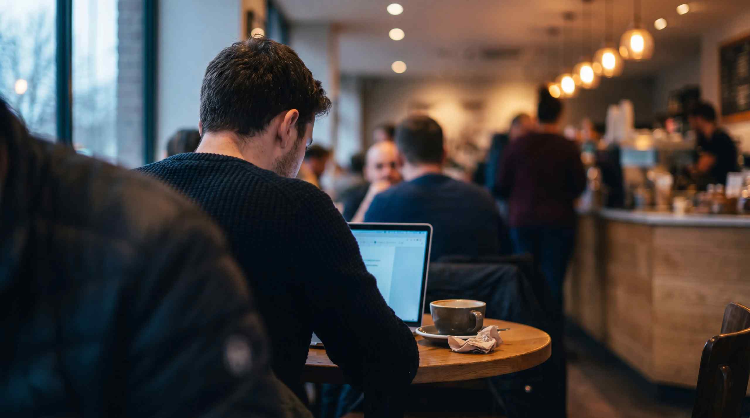 A man in a coffee shop on a laptop.